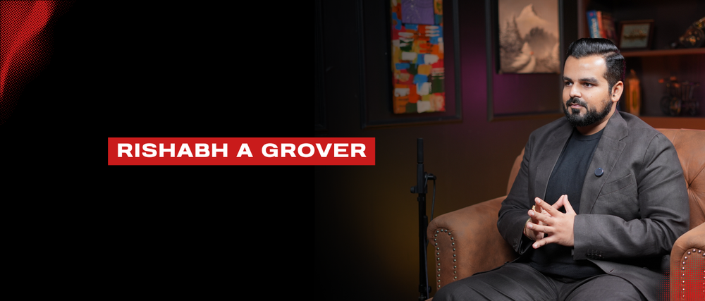 Business professional Rishabh A Grover seated in a modern office setting, portraits in background.