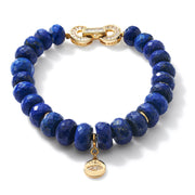 Faceted blue gemstone beaded bracelet with gold clasp and gold charm on white background