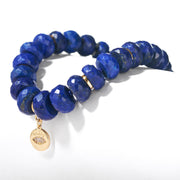 Faceted lapis lazuli beaded bracelet with gold charm on white background